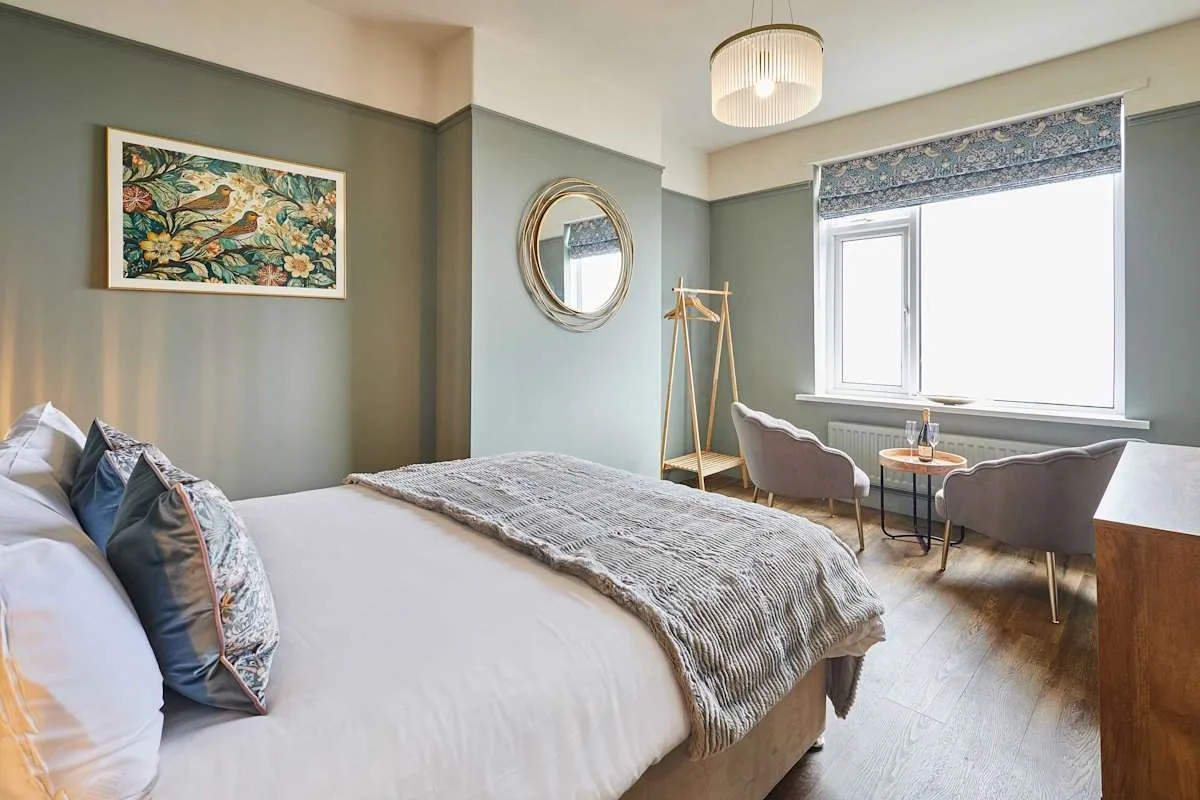 Dormitorio con una cama grande y una zona de estar junto a la ventana.