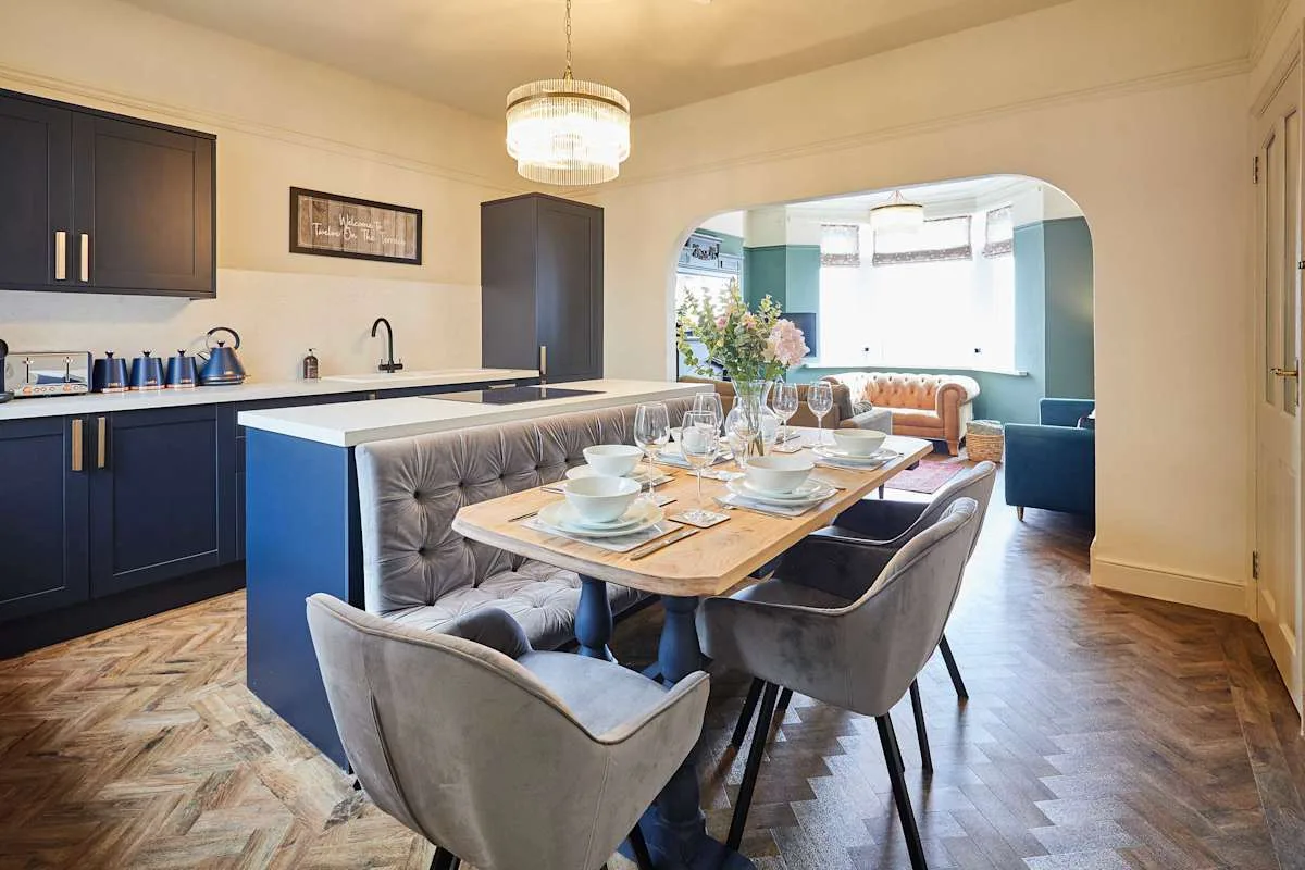 Un comedor con la mesa puesta se abre a una sala luminosa.