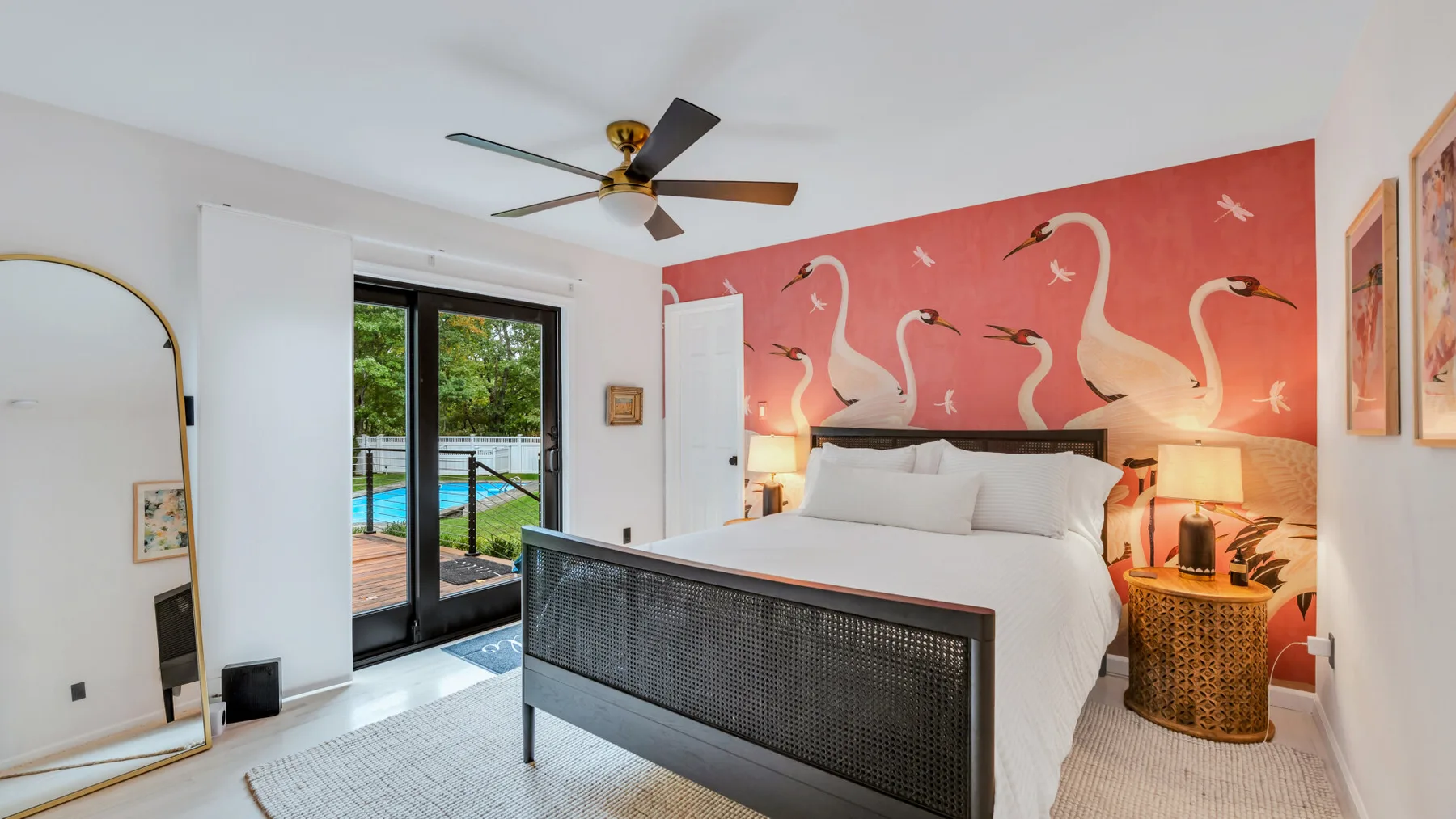 A bedroom with a large bed and a coral wall mural of swans.