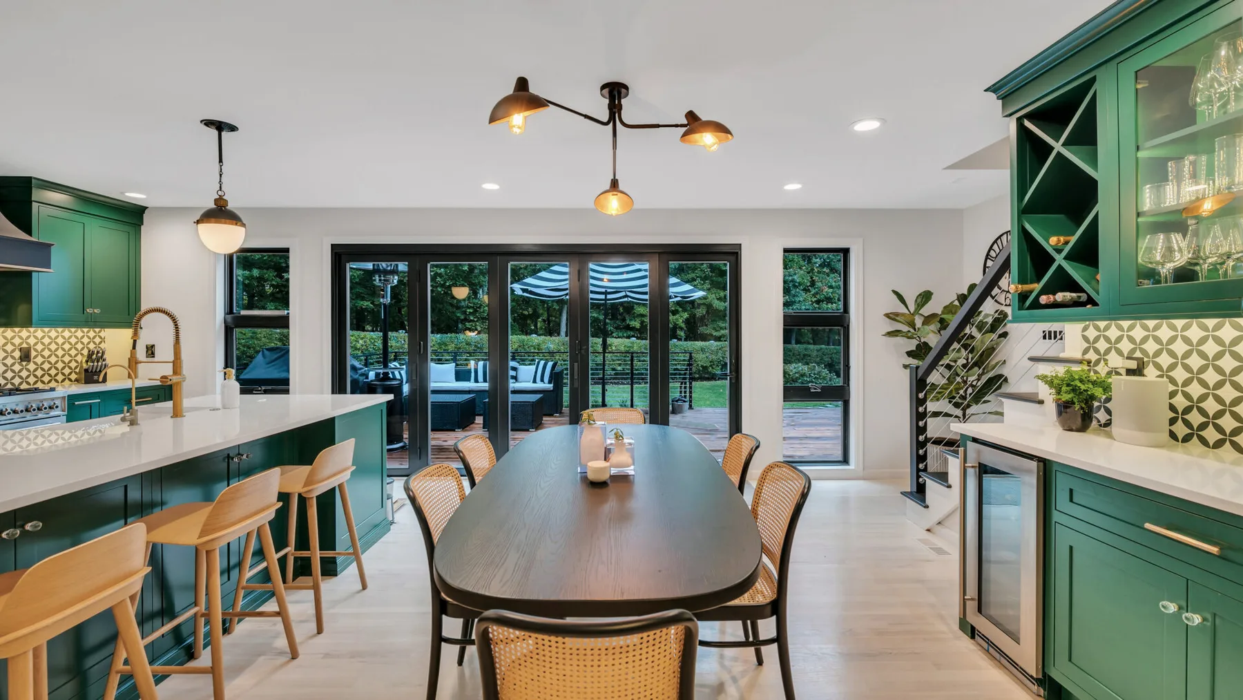 A bright open-plan kitchen and dining area with green cabinetry and a long dining table.