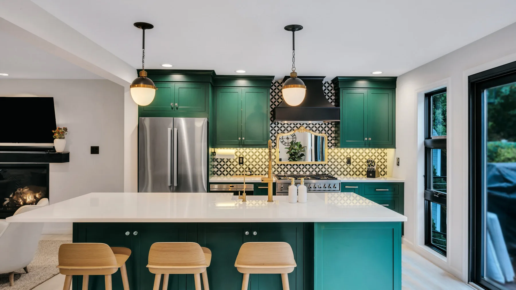 A kitchen with green cabinets, a central island, and pendant lights.