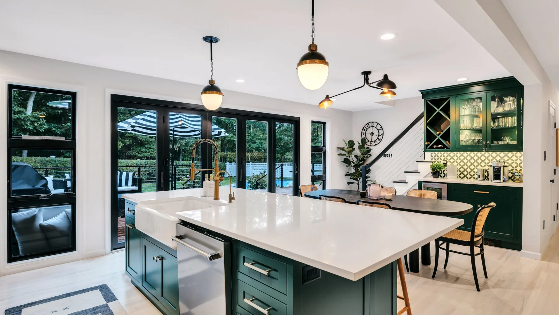 A bright kitchen features a large island and dark green cabinetry.