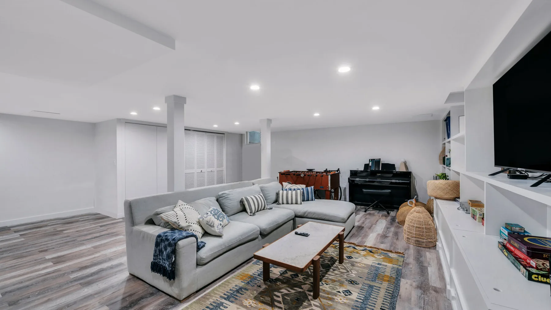 A bright living room with gray seating, a coffee table, and a television.