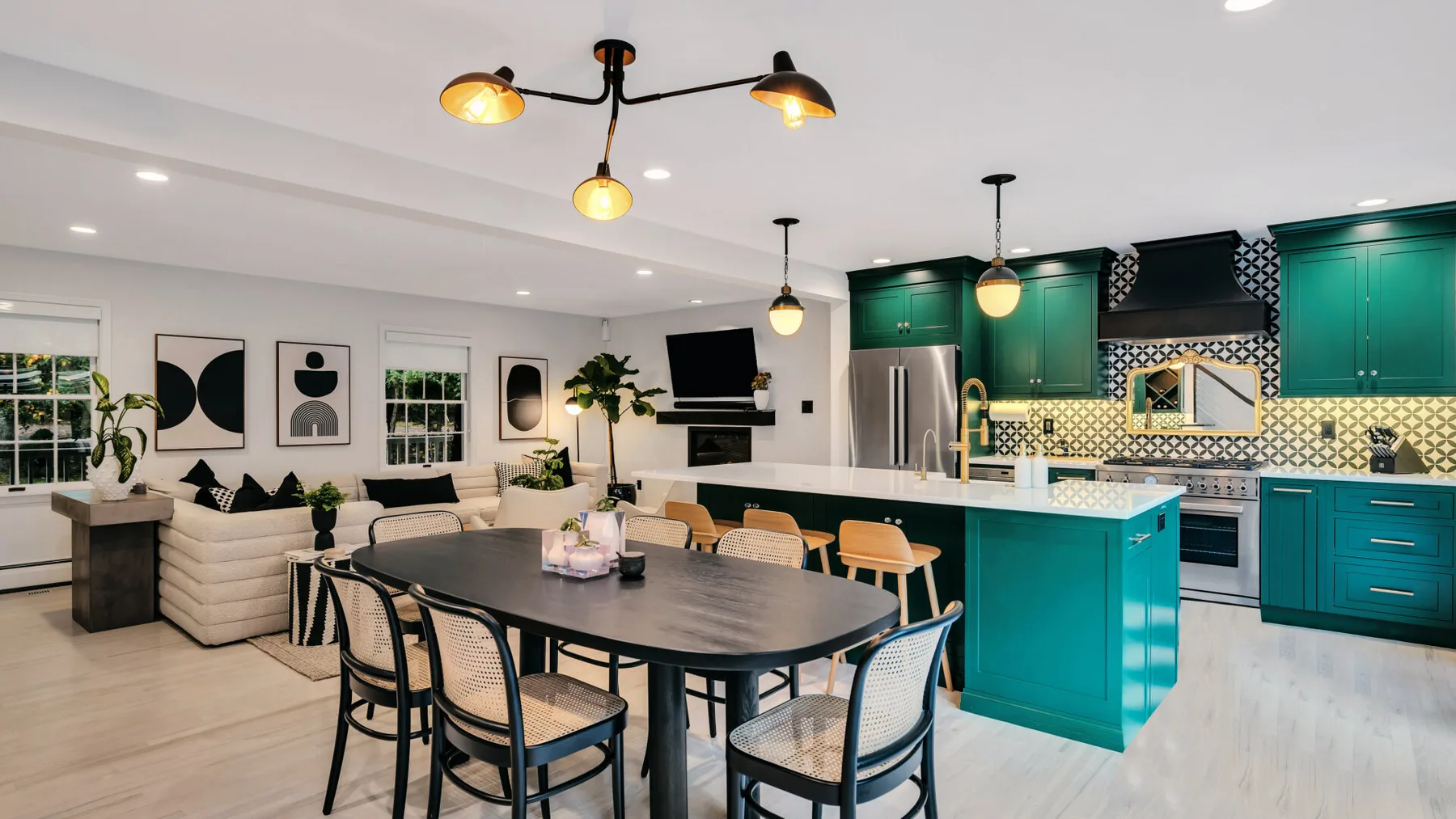 An open-plan kitchen and dining area with green cabinets and a long dining table.