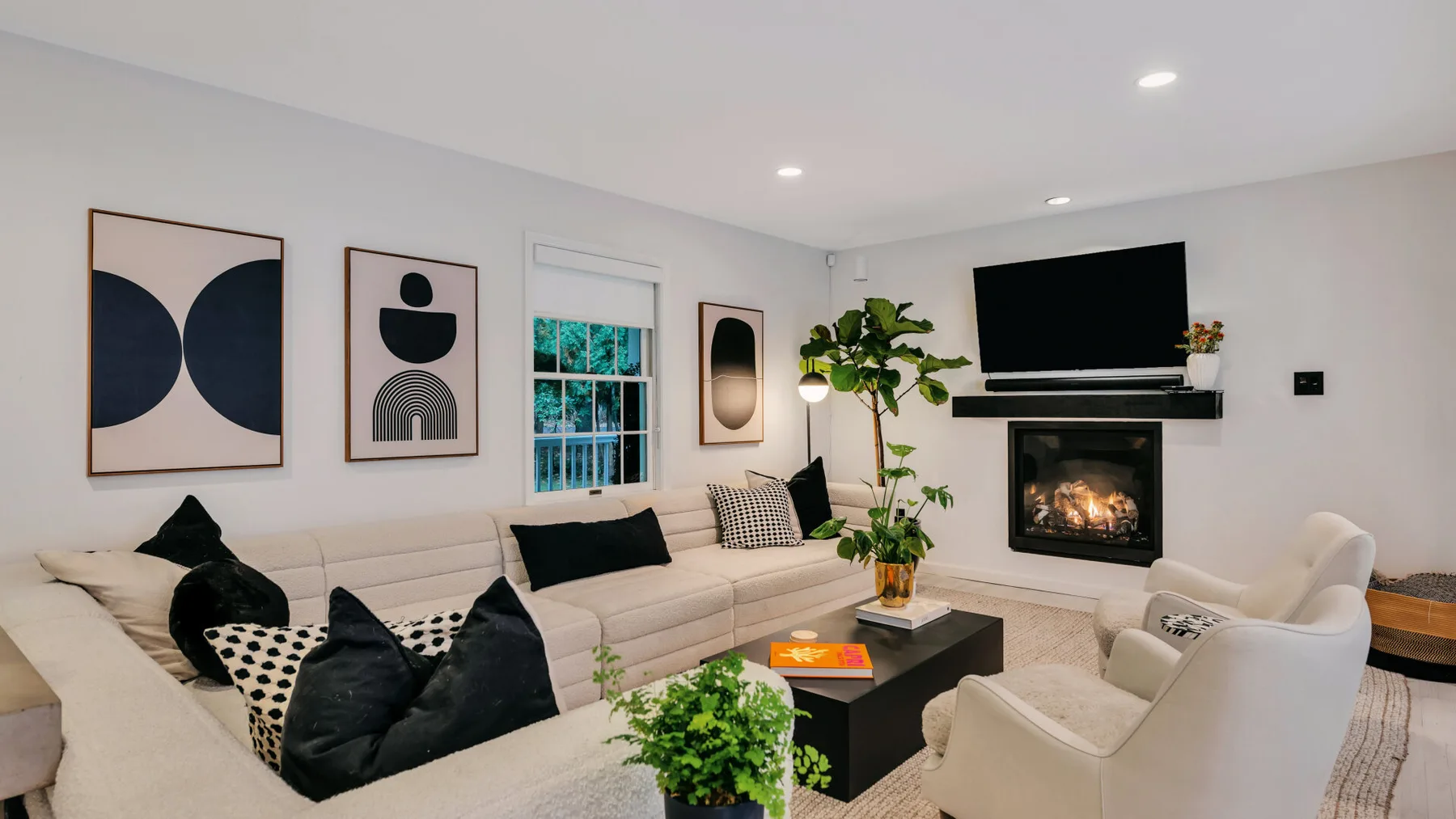 Una sala luminosa con asientos claros, arte enmarcado y una chimenea.