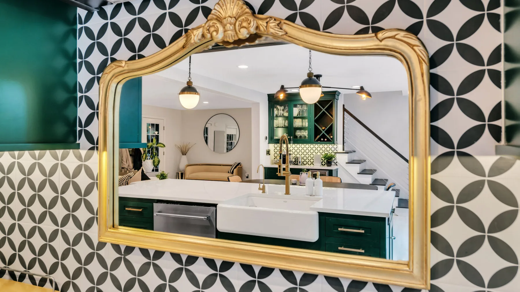 A kitchen with a large ornate mirror reflecting a dining area and staircase.