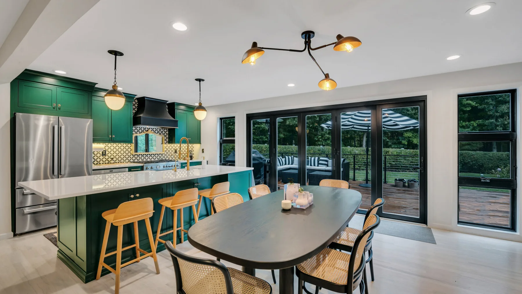 A modern kitchen and dining area with a long table beside large glass doors.