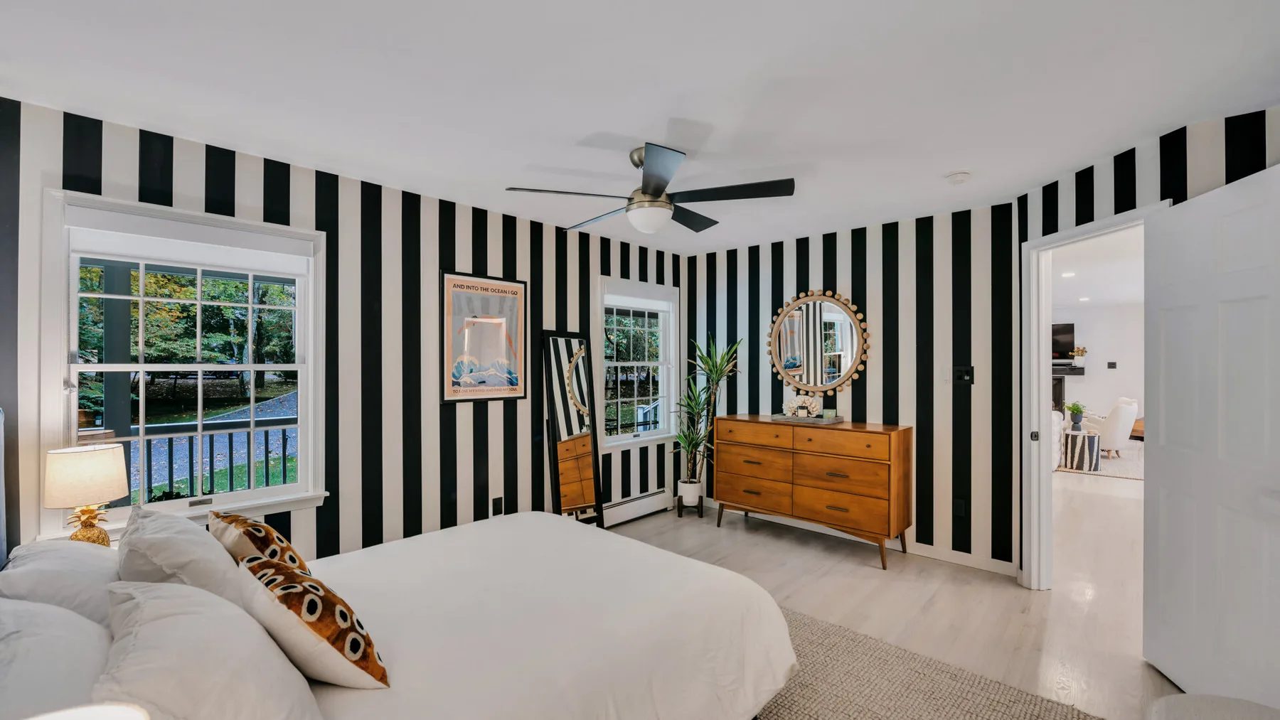 A bedroom with a large bed, striped walls, and a wooden dresser.