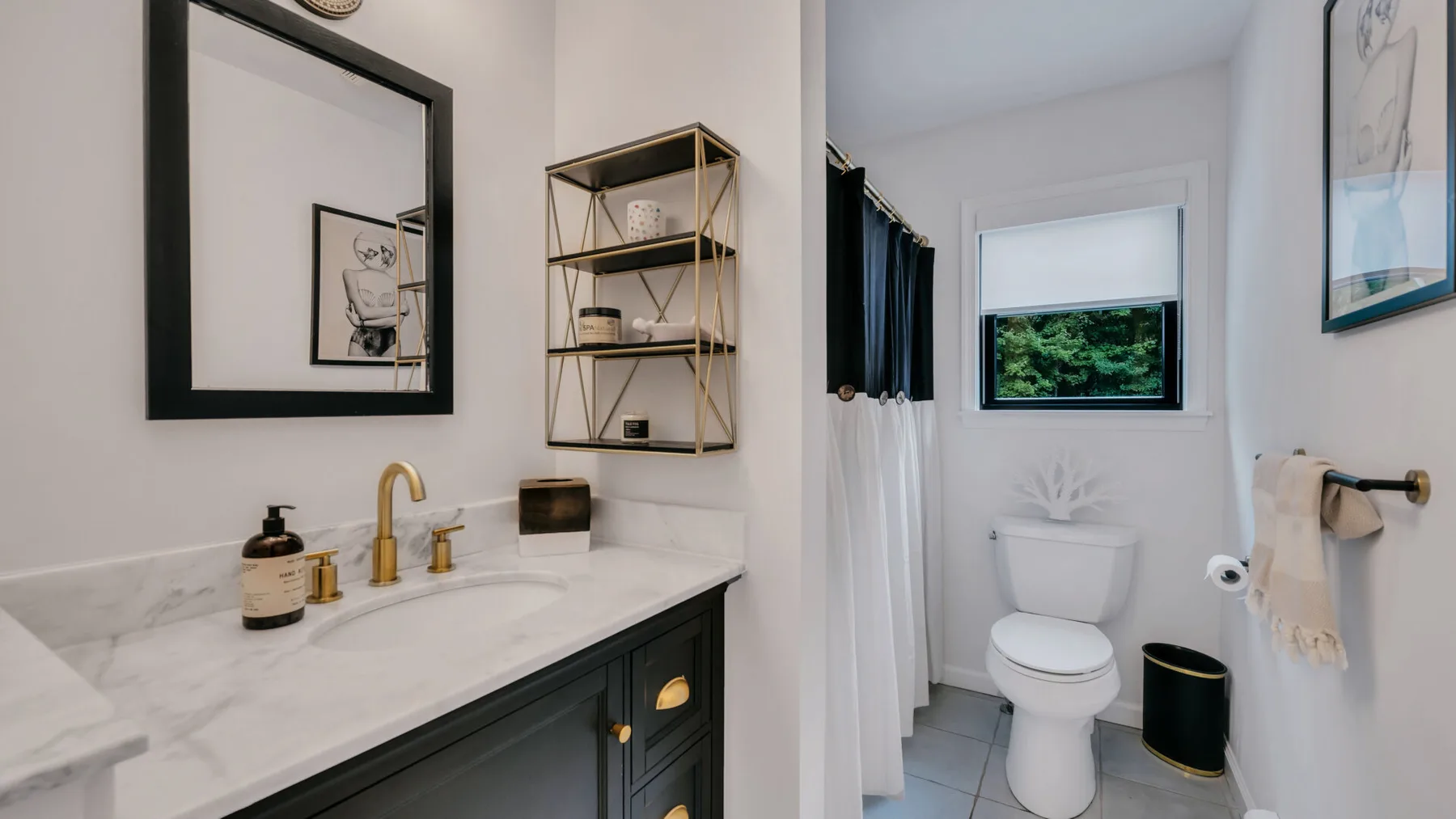 A bathroom with a white vanity and toilet beside a curtained shower.