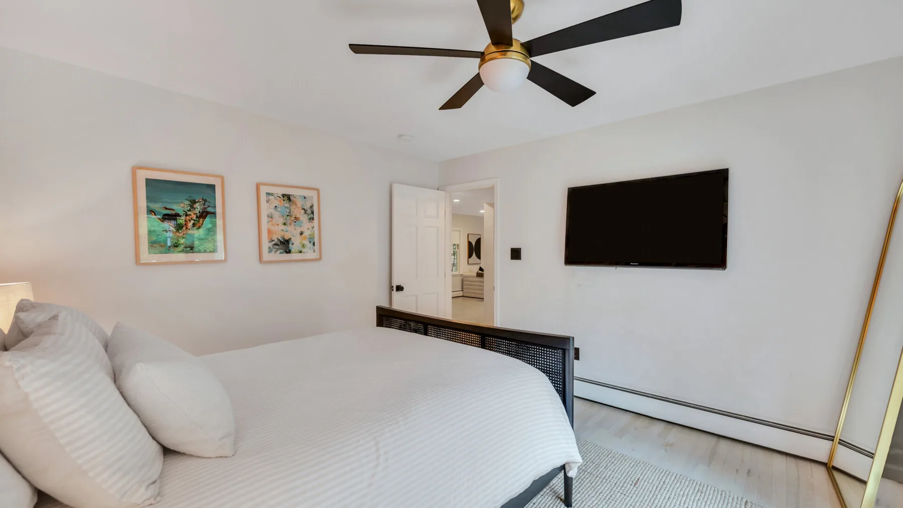 A bedroom with a neatly made bed and a wall-mounted television.