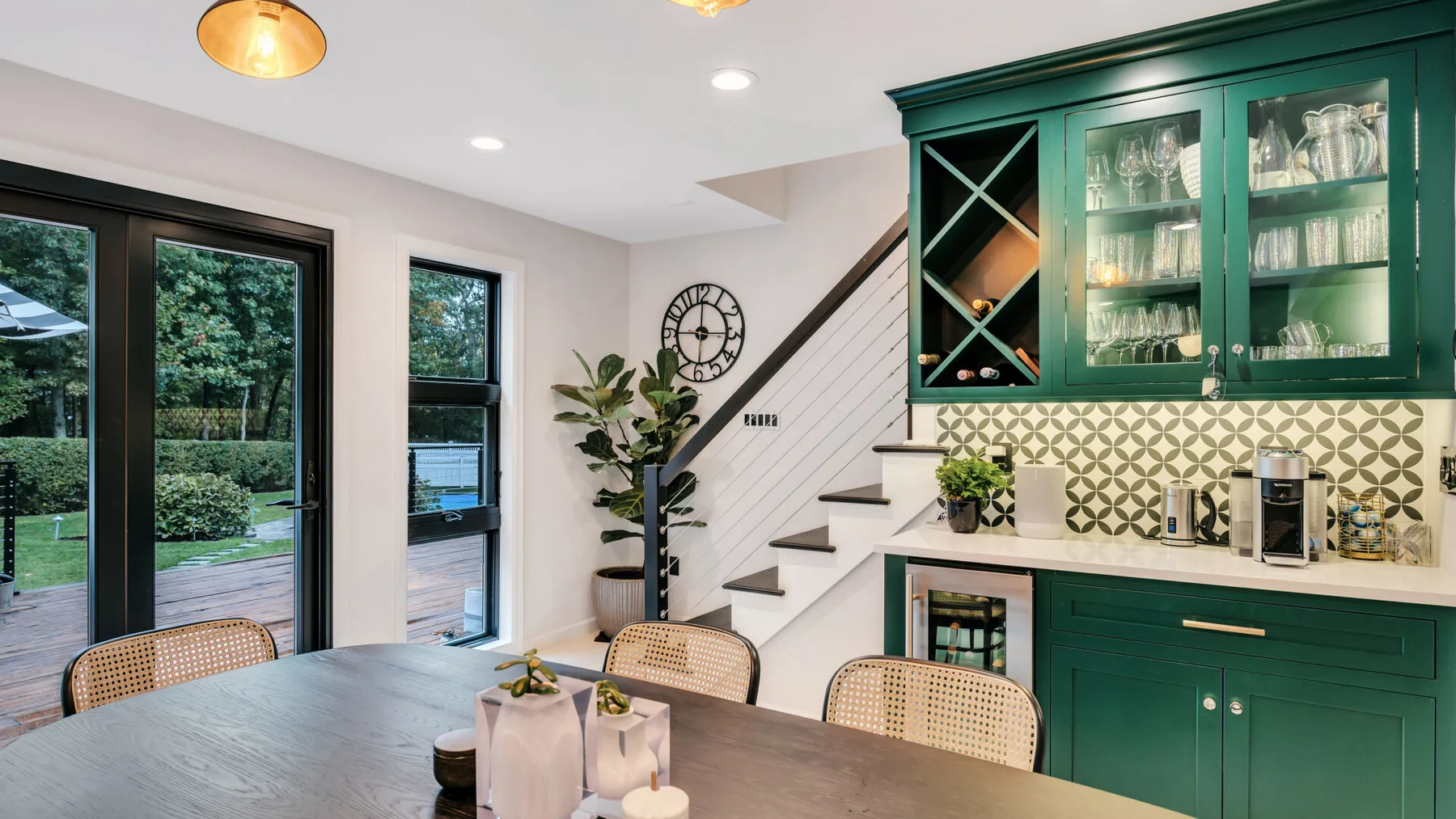 A kitchen and dining area with green cabinetry, a table, and stairs.