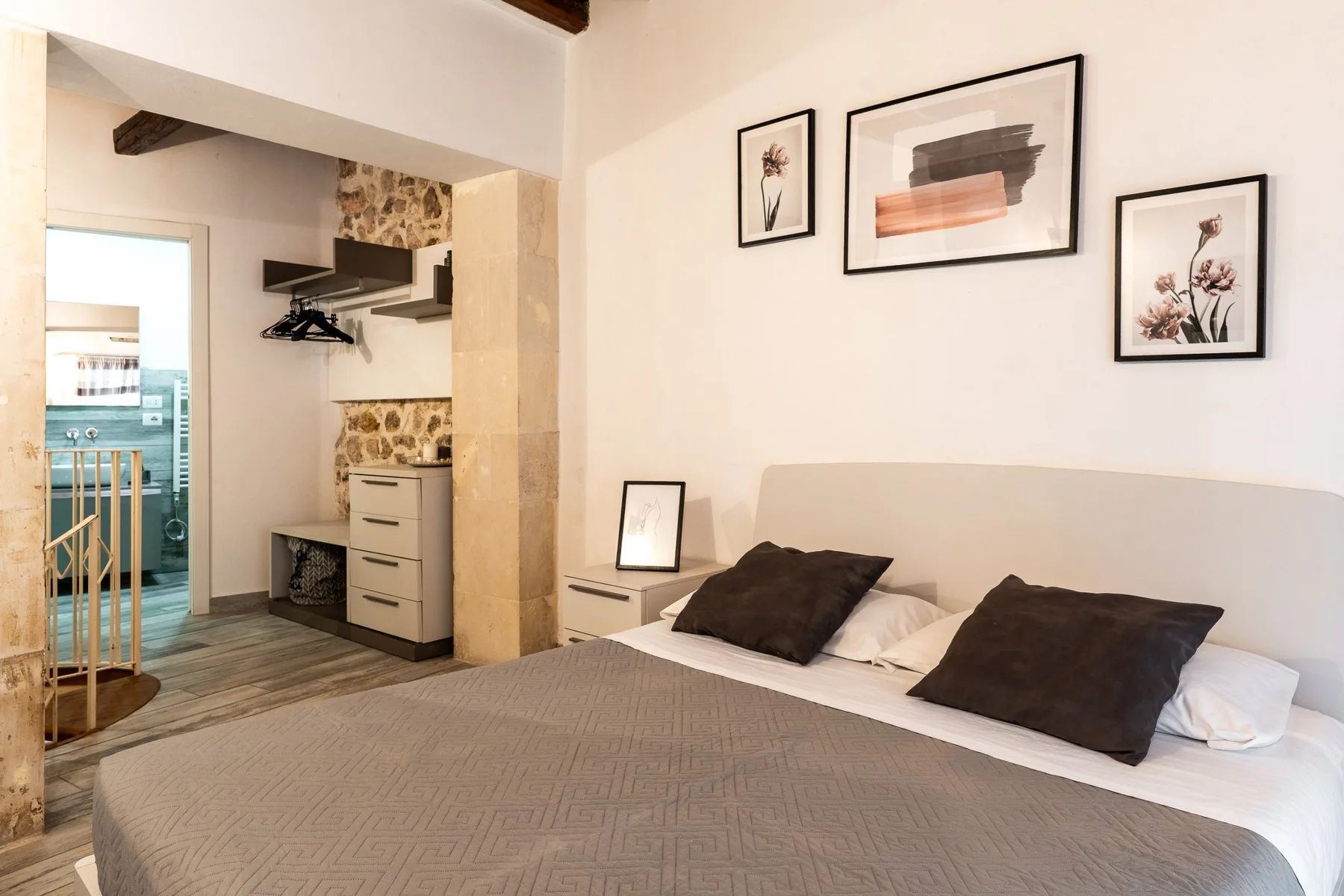 Un dormitorio con una cama ordenada y una zona de armario abierta.