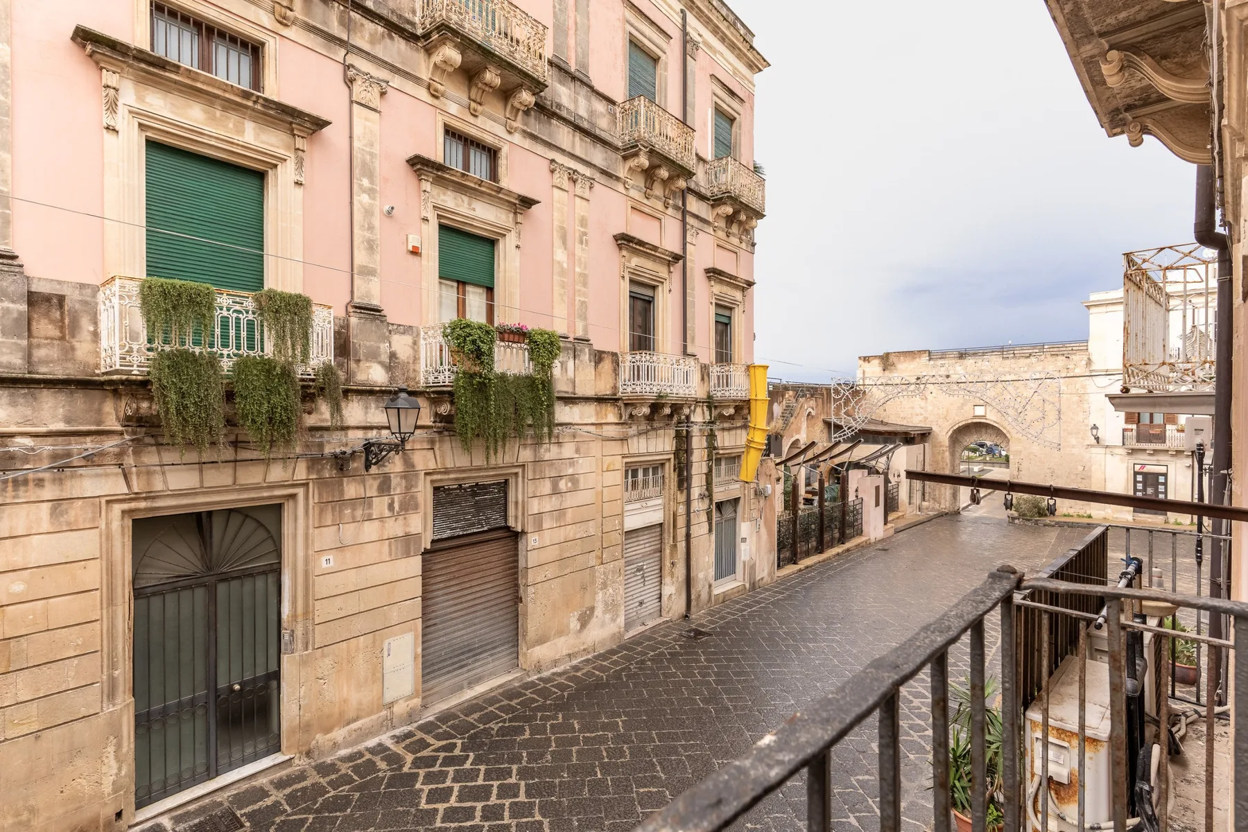 Una calle estrecha empedrada pasa entre edificios antiguos y un arco de piedra.