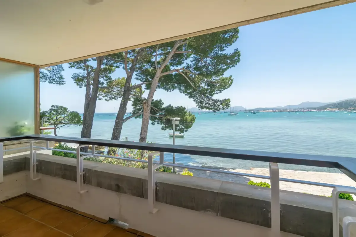 A covered balcony overlooks the sea, with trees along the shoreline.