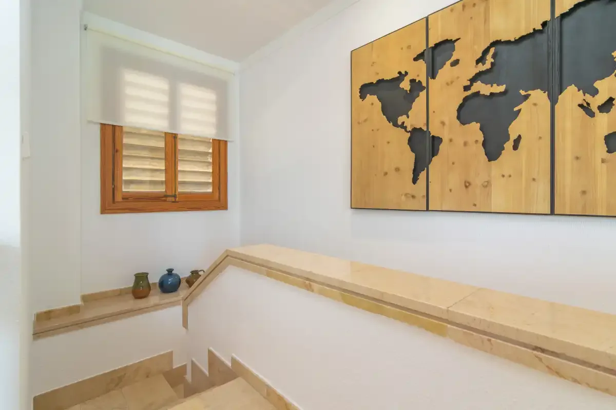 A stair landing with a window and a world map wall decoration.