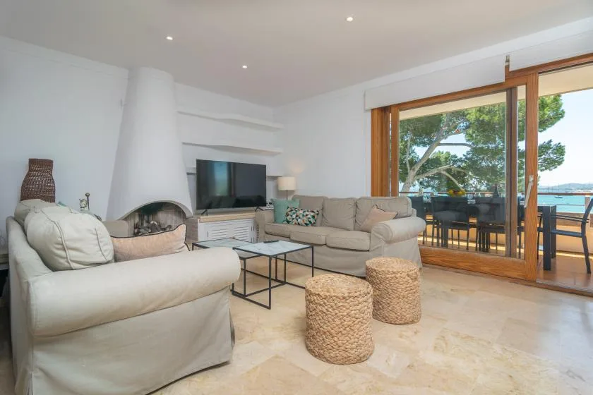 A bright living room with seating, a television, and large glass doors opening onto a terrace.
