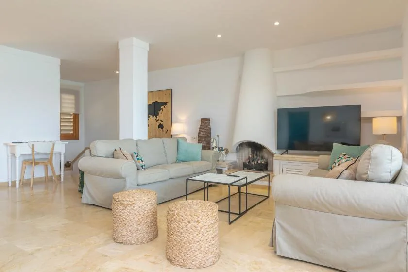 A bright living room with seating arranged around a coffee table and television.