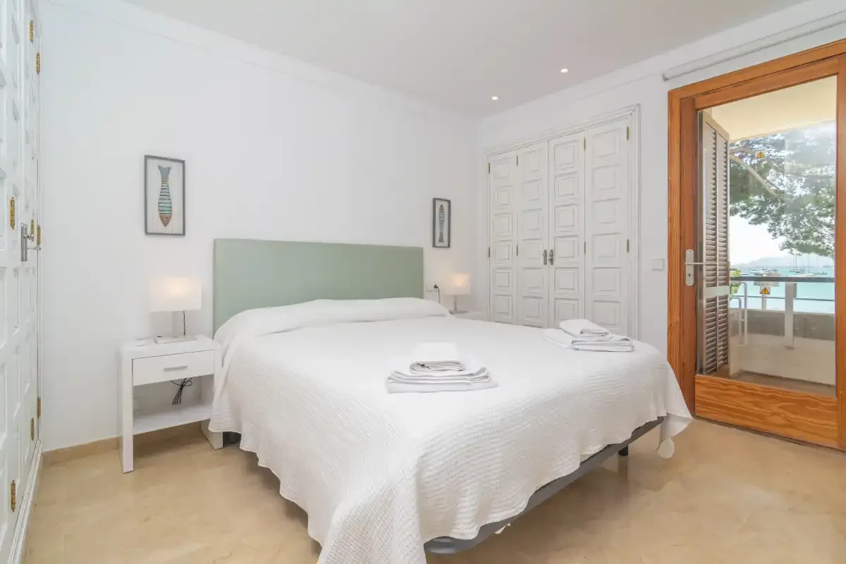A bright bedroom with a large bed and an open doorway to a balcony.