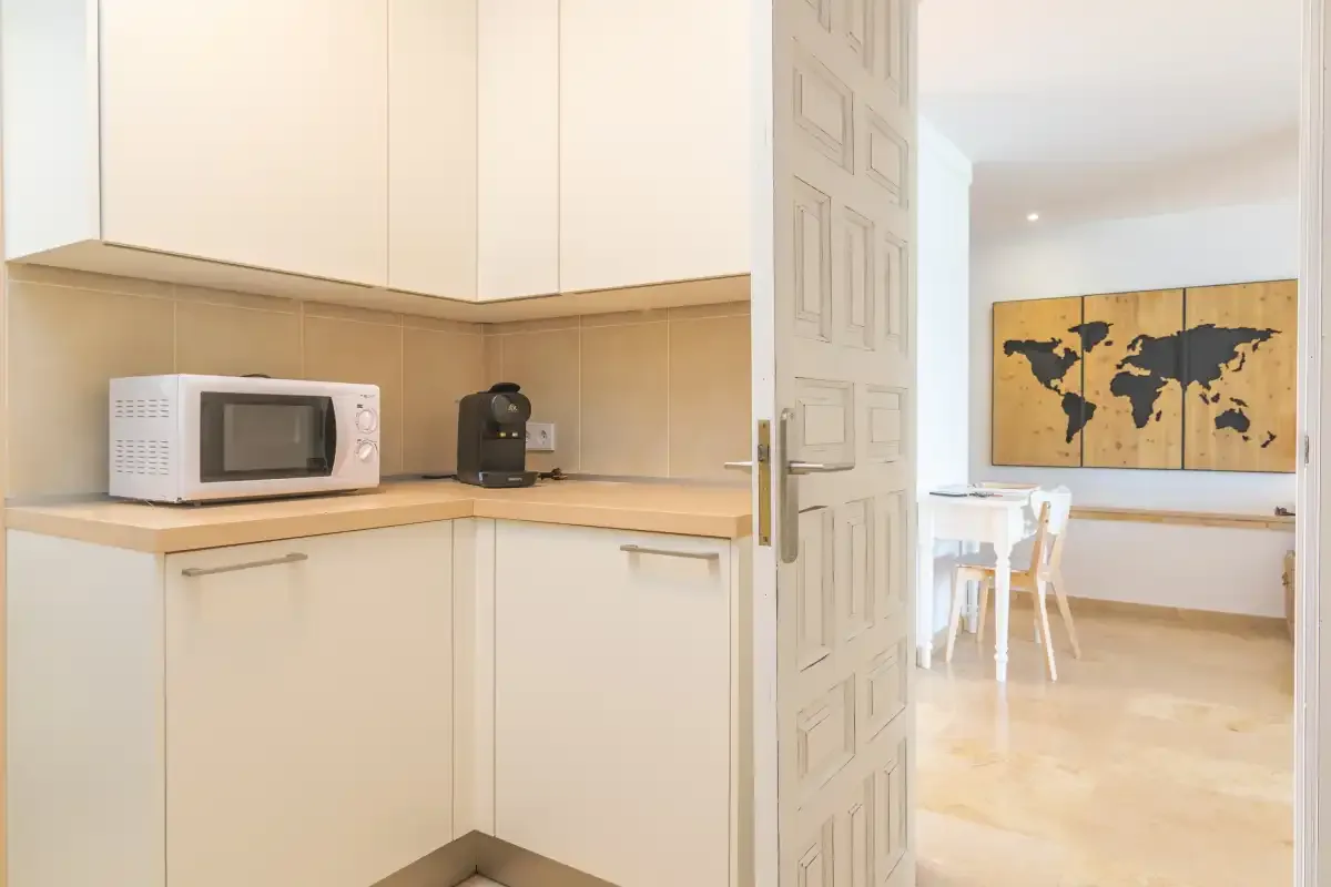 A bright kitchen with a microwave and coffee machine beside a dining area.