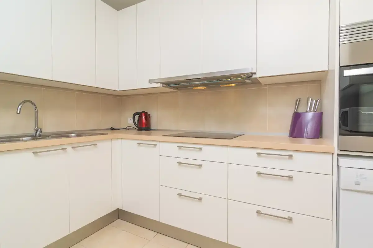 A bright kitchen with white cabinets, a cooktop and a sink.