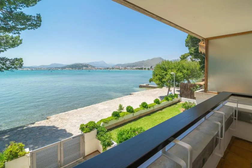 A waterfront balcony overlooks the bay, with a narrow strip of lawn beside the shore.