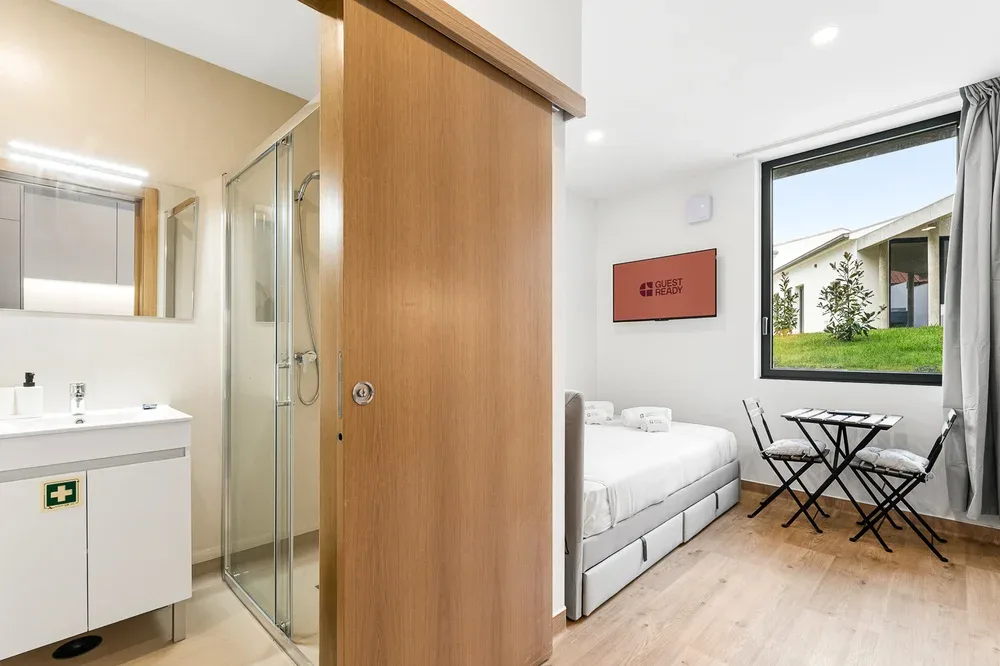 A bright room with a bed, folding table and chairs beside a window.