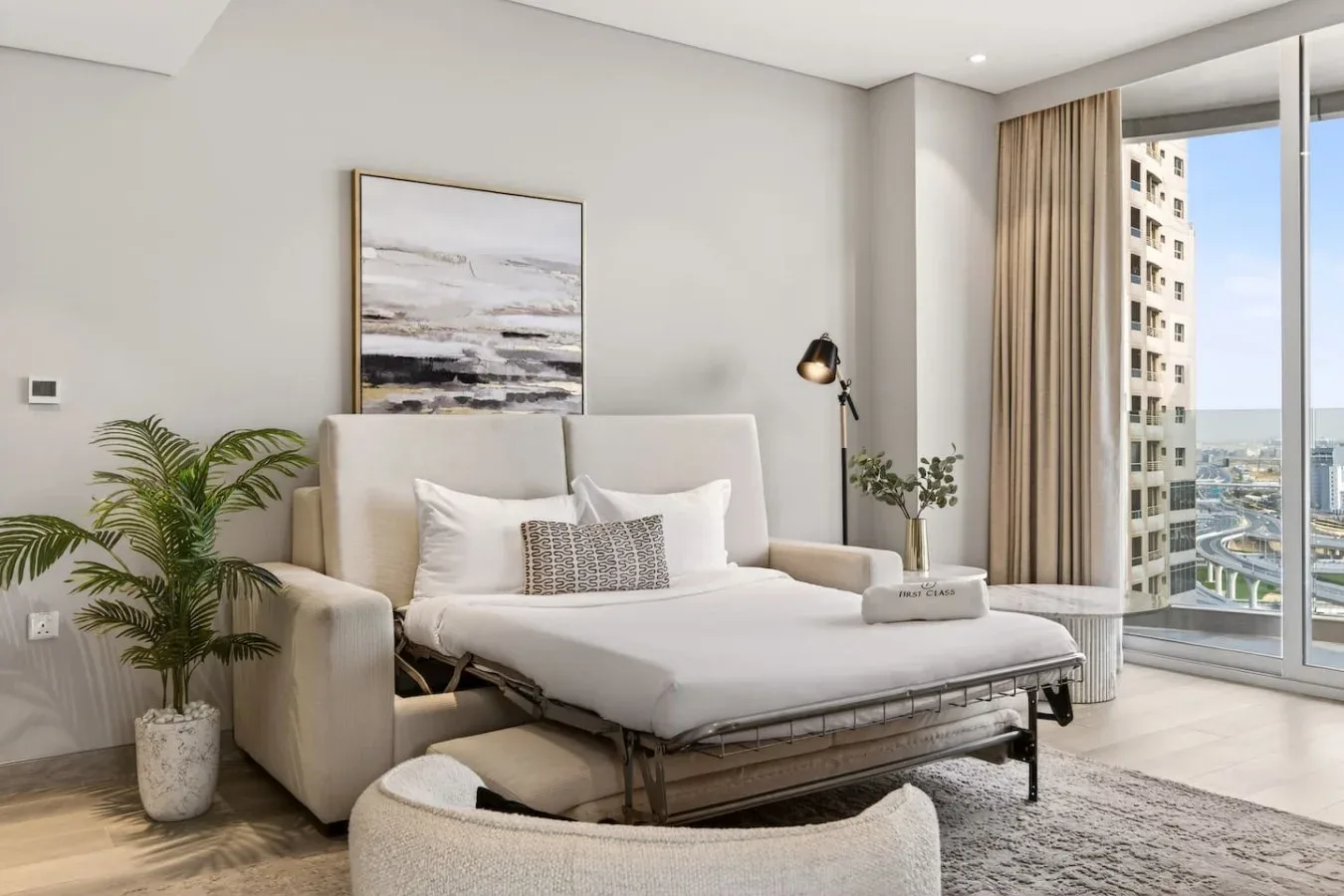 Un dormitorio luminoso cuenta con una cama junto a ventanales.