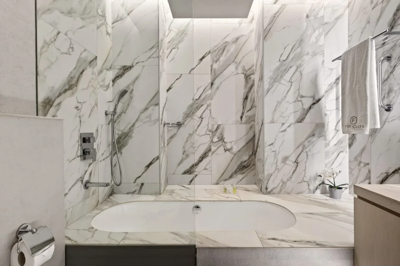 Un baño con una bañera empotrada en un revestimiento con vetas de mármol.