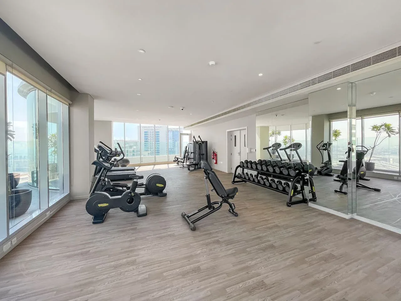 Una sala de fitness luminosa con bicicletas estáticas, pesas y paredes con espejos.