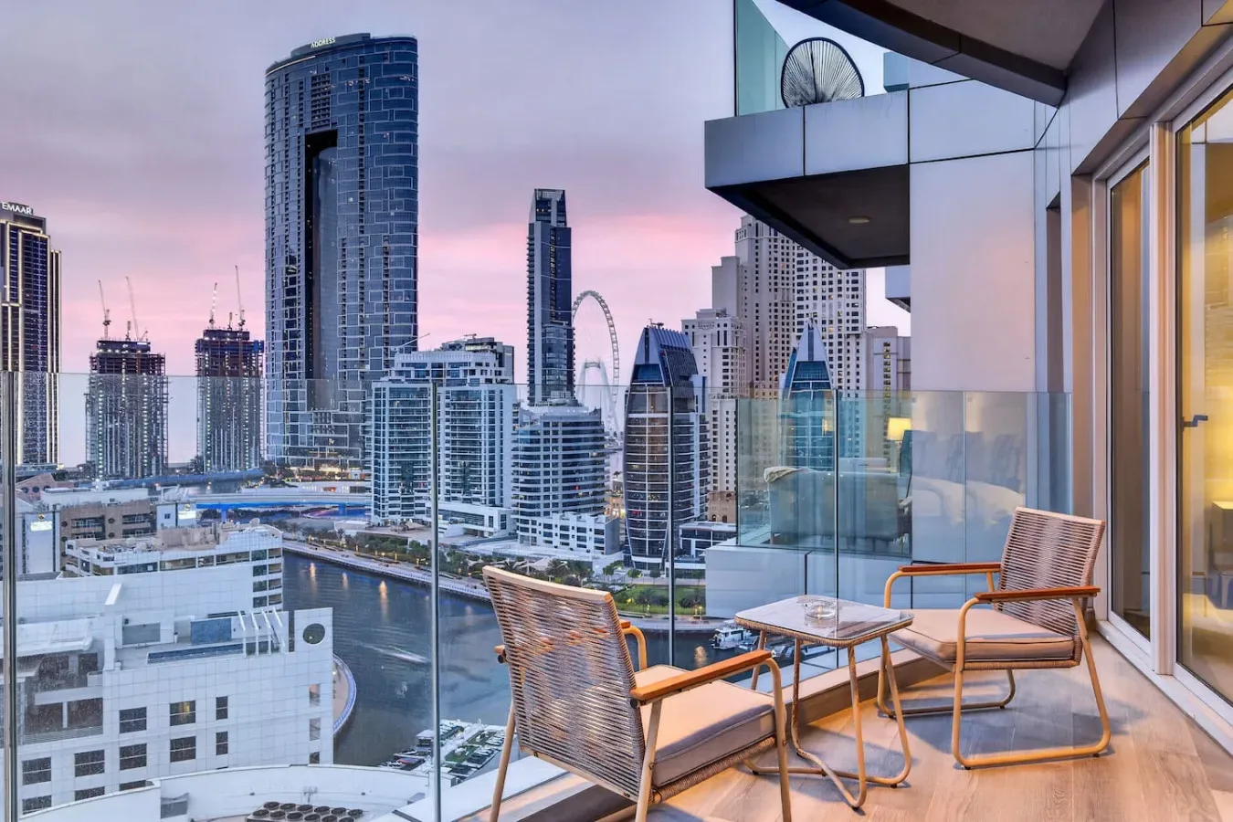 A balcony seating area overlooks a city skyline at dusk.