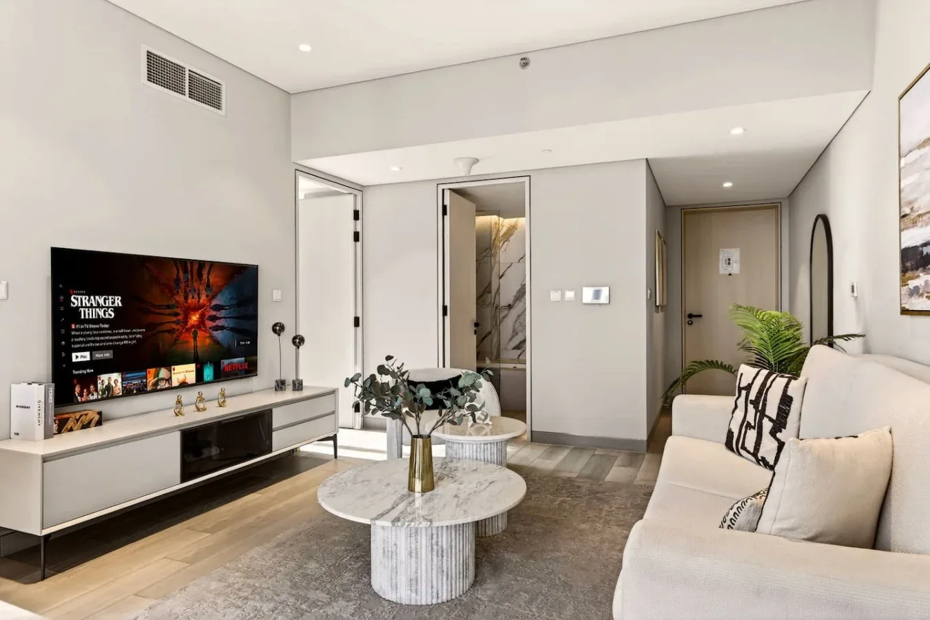 Una sala luminosa con televisor, asientos y una mesa de centro redonda.