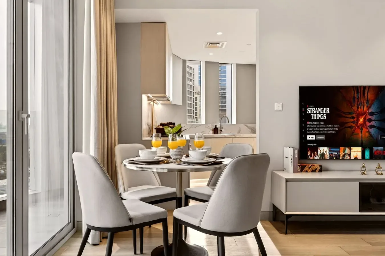 A dining area with a set table beside a kitchen and a television.
