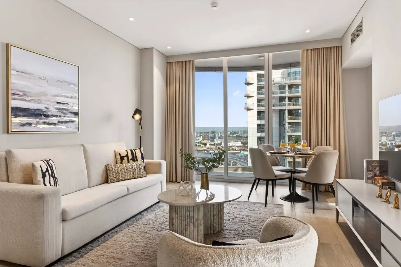 A bright living room with seating beside a dining table and large windows.