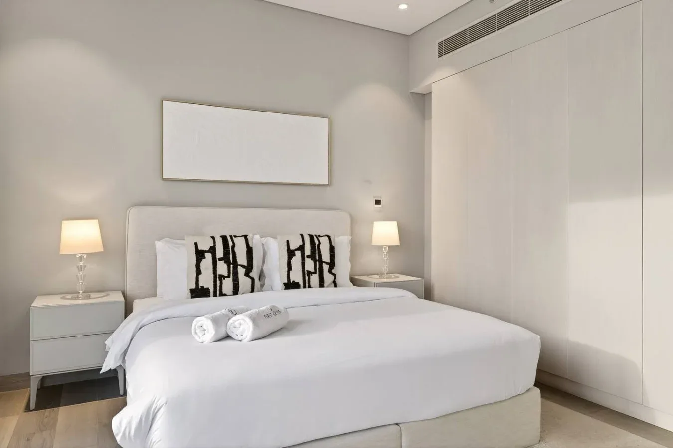 Un dormitorio luminoso con una cama bien arreglada y lámparas de mesilla a juego.