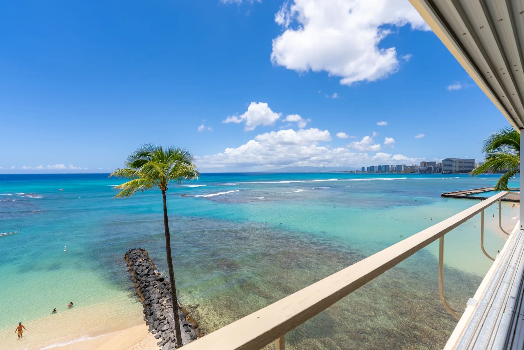 Balcony overlooking a turquoise ocean and a sandy beach.