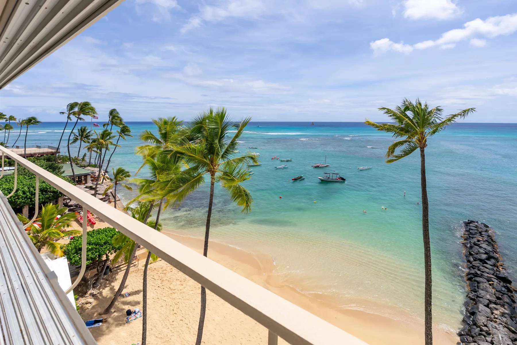 A tropical beach and turquoise sea are visible from a balcony.