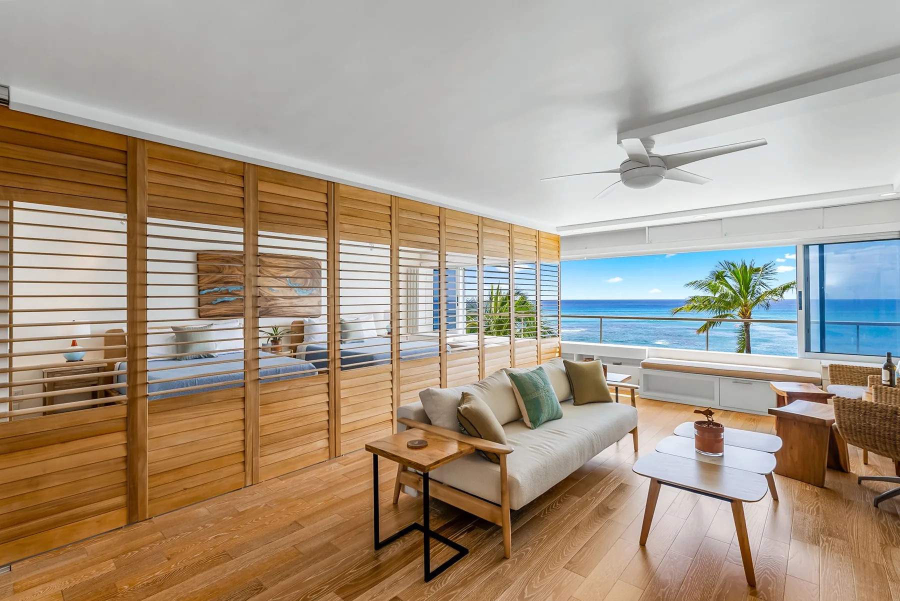 A bright living room opens onto a balcony with ocean views.