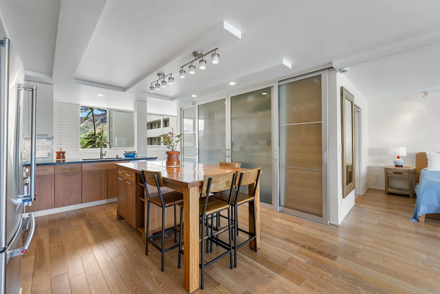 An open kitchen and dining area with a wooden table and large frosted-glass panels.