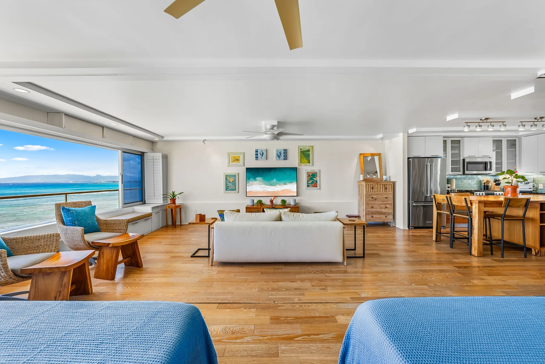 A bright living room opens onto a wide ocean view through large windows.