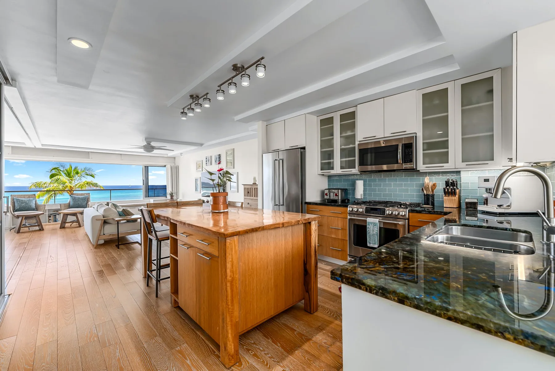 A bright open-plan kitchen with a wooden island and a dining area beside large windows.