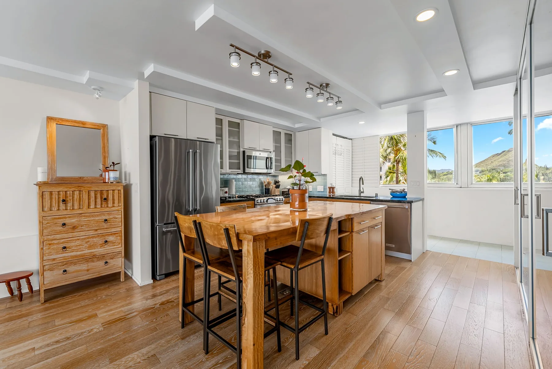 A bright kitchen and dining area with a wooden table and large windows.
