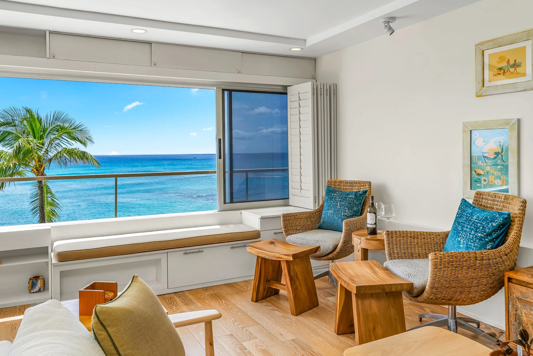 A bright living room opens onto a sea view through a large window.