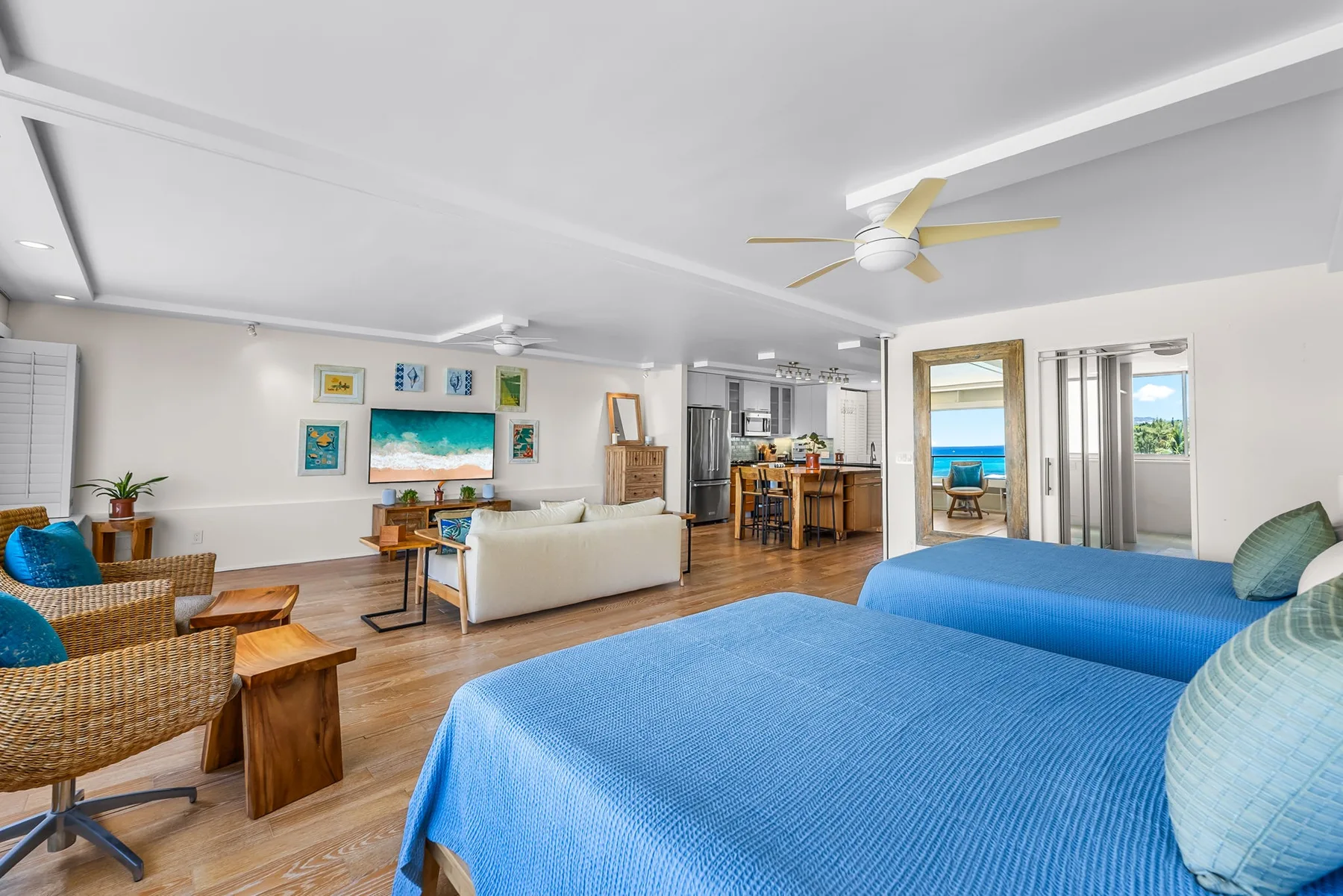 A bright living room with blue beds in the foreground and a dining area beyond.