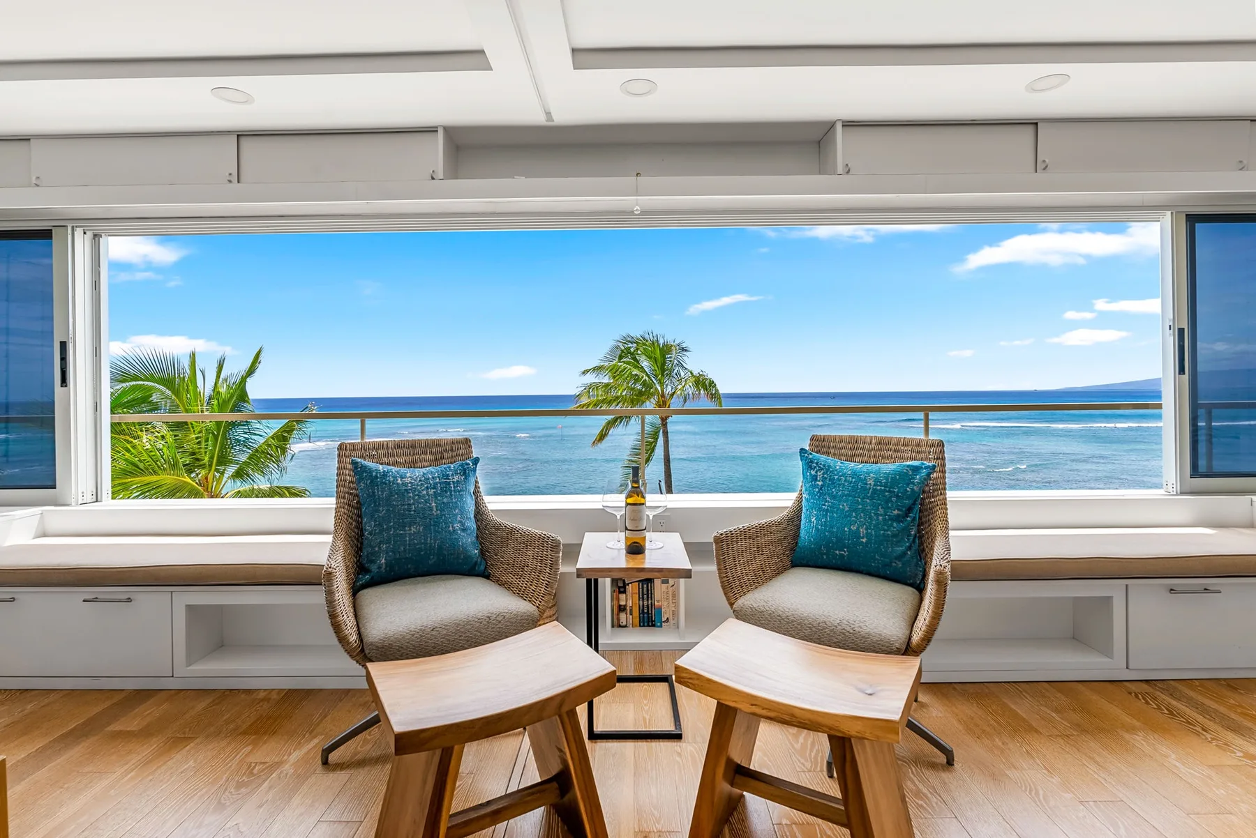 A sitting area with two cushioned seats faces a wide window overlooking the ocean.