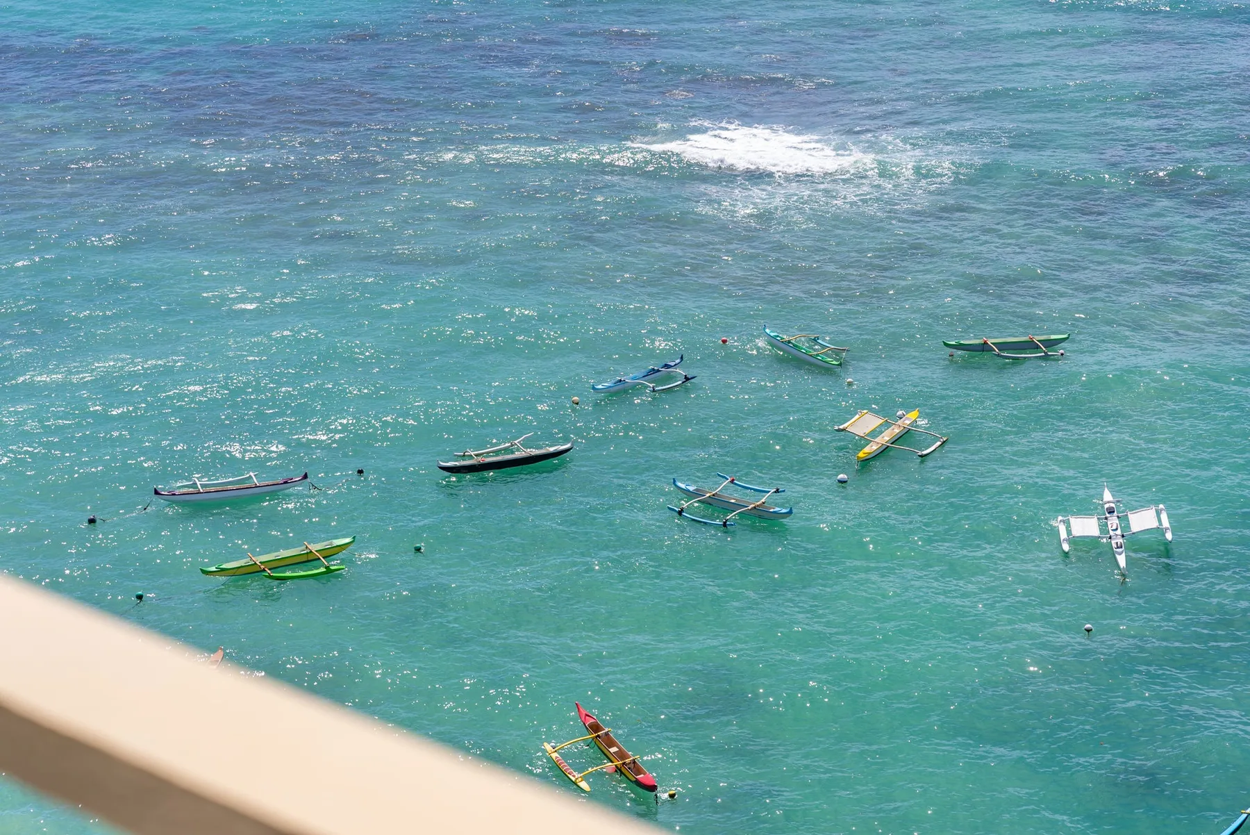 Small boats float on turquoise water beside a sunlit shoreline.