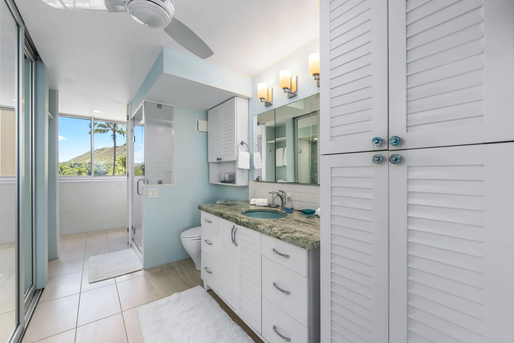 A bright bathroom with a long vanity, mirrors, and a glass shower.