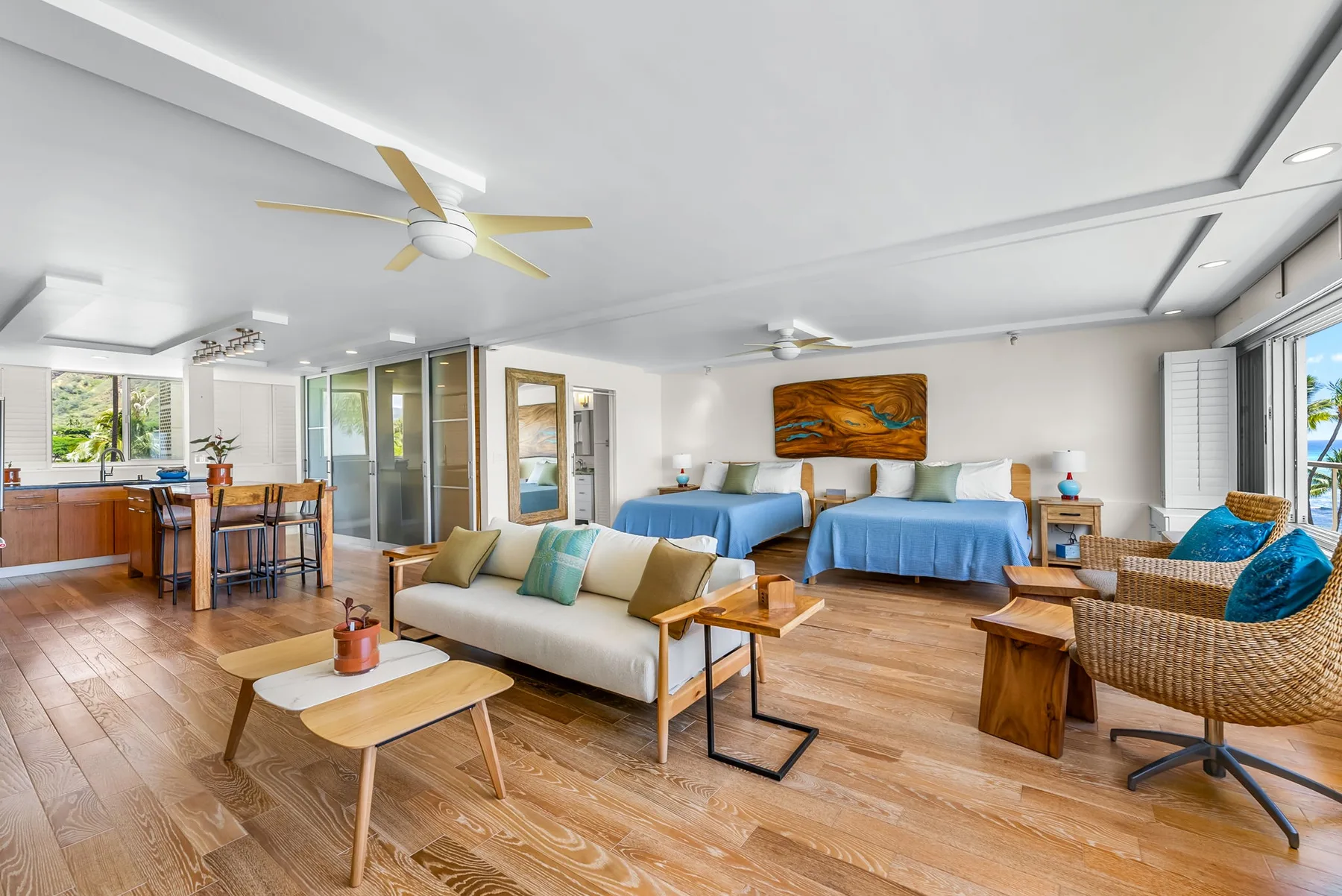 A bright open room combines a living area, two beds, and a dining table.