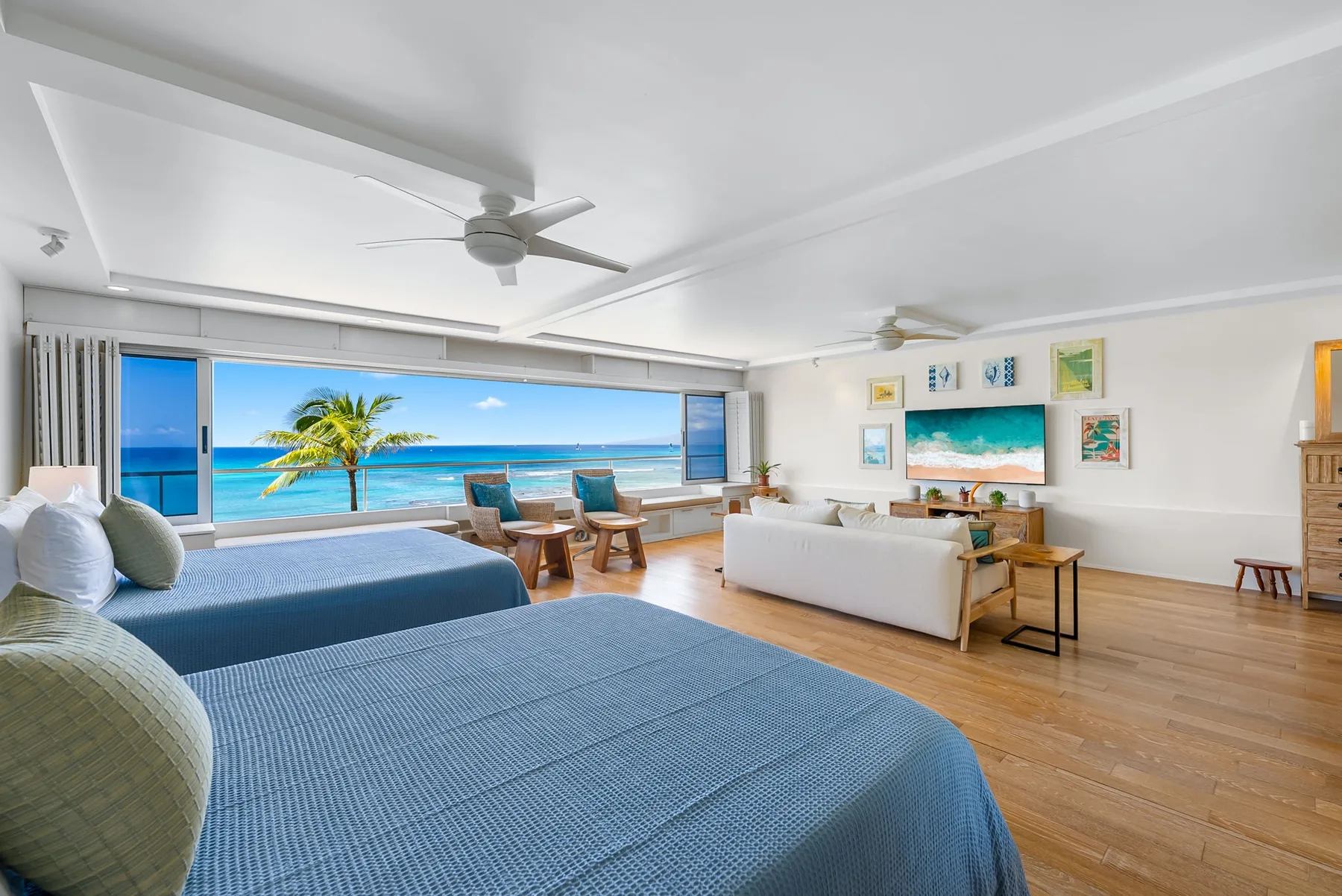 A bright bedroom with a bed, seating area, and wide ocean views.