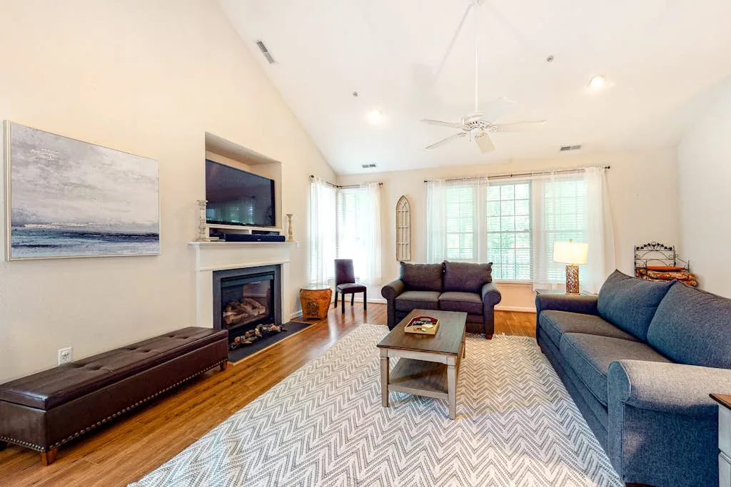 A living room with seating arranged around a coffee table and fireplace.