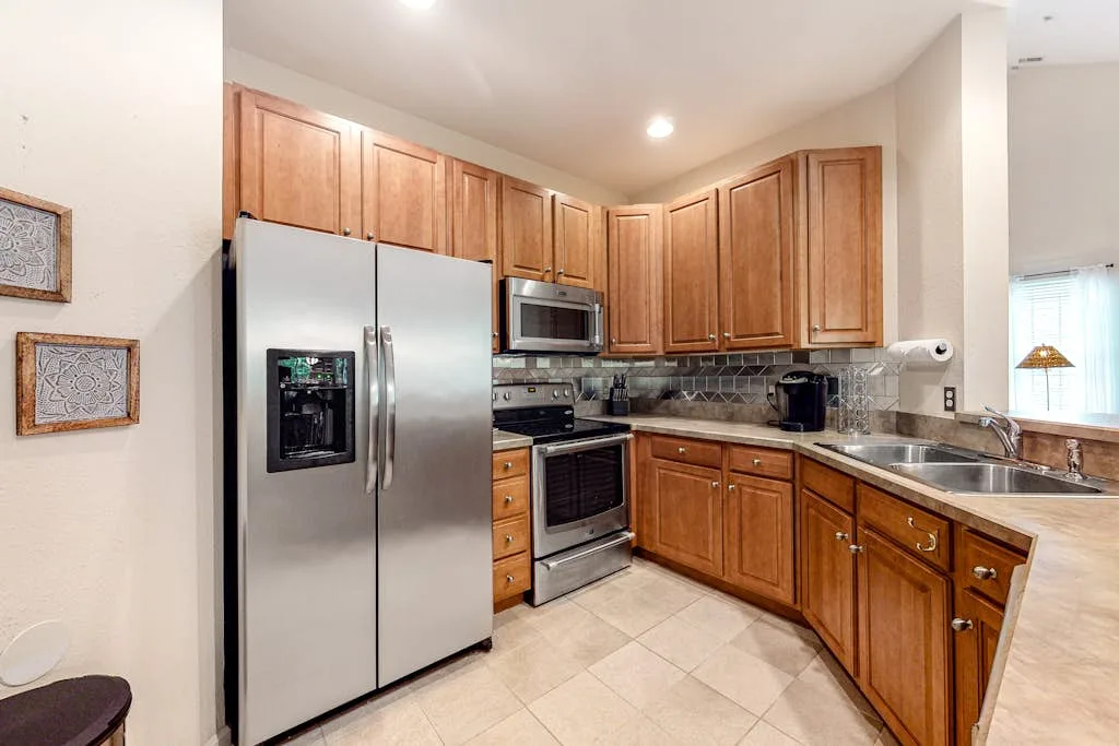 A kitchen with wooden cabinets, stainless steel appliances, and a tiled floor.